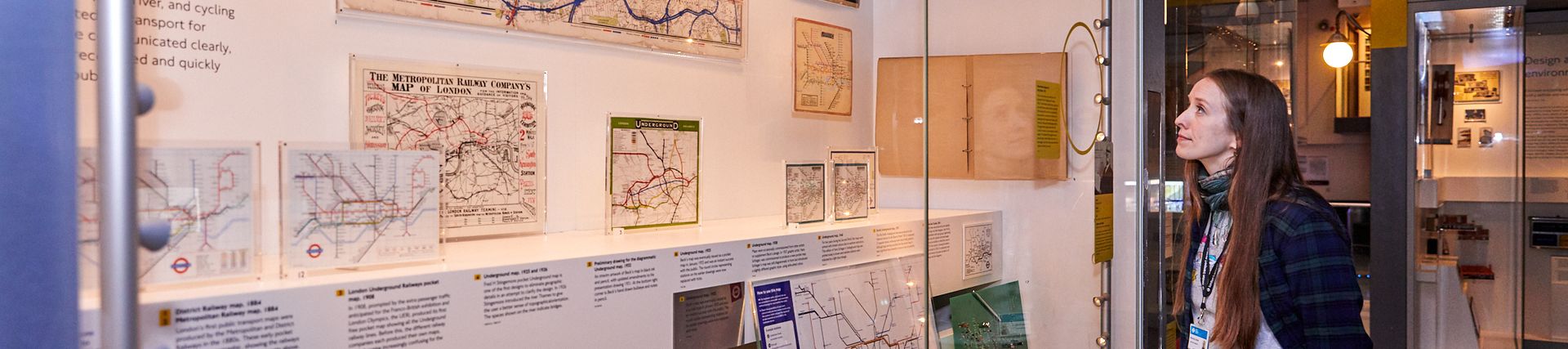A young woman looks at a display of old underground maps