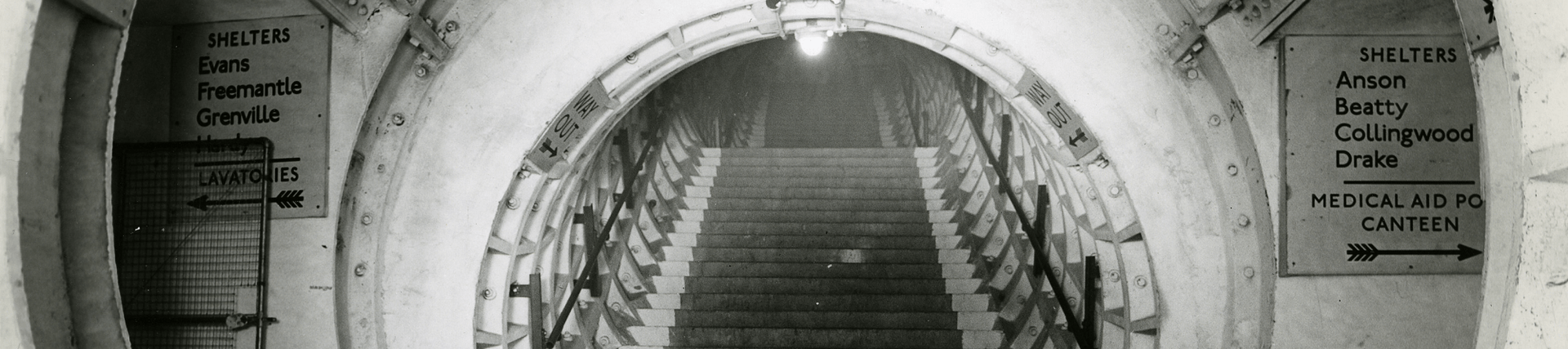 Black and white photo of an underground tunnel with stairs going up
