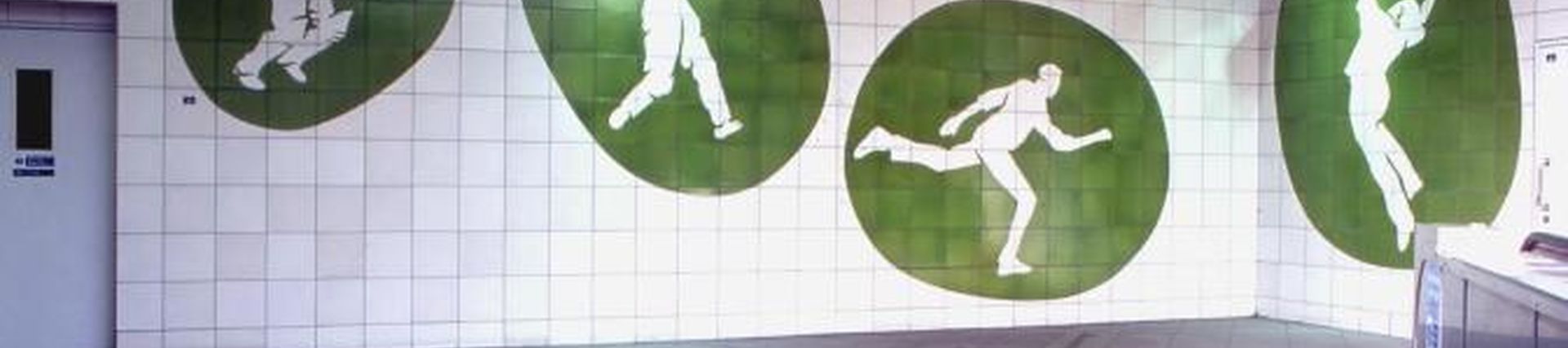 The hall of Oval station with white and green tiles depicting cricket players