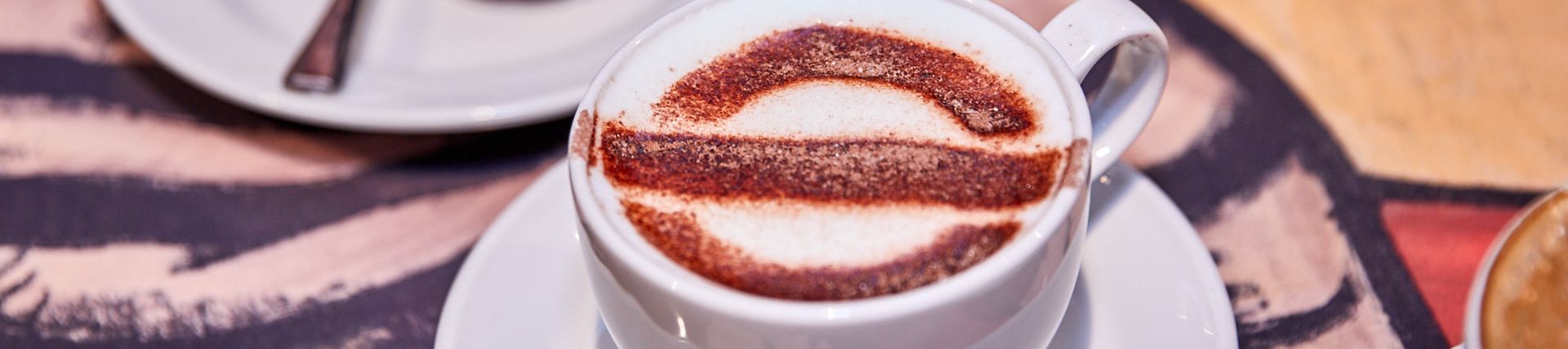 A cappuccino decorated with a roundel in a white mug