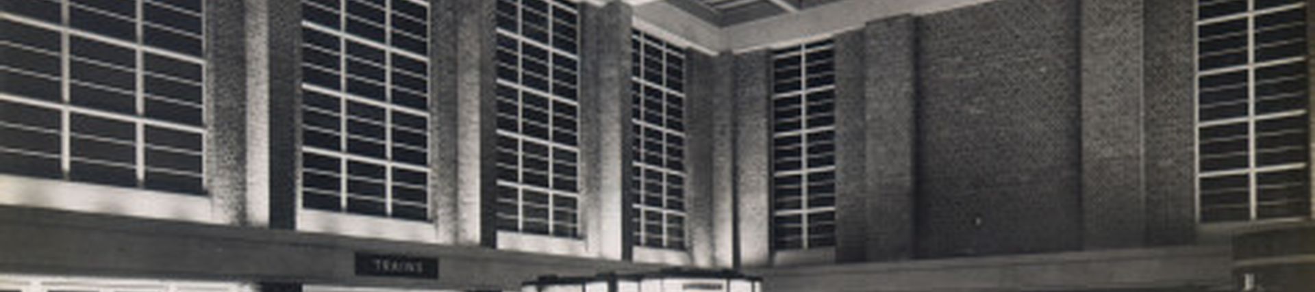 Black and white photo of old station ticket hall taken at night