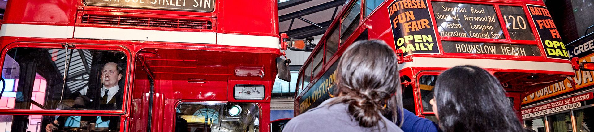 Two young women looking at two routemaster buses on display at the museum