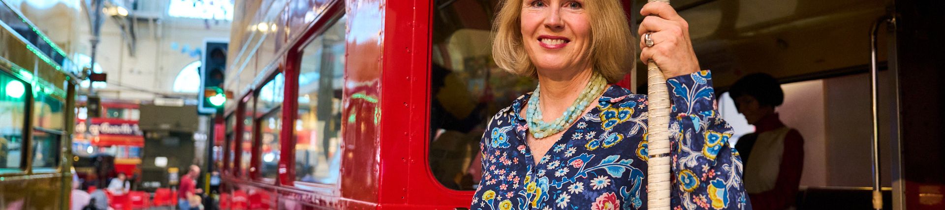 Elizabeth stands at the back of a vintage Routemaster bus in London Transport Museum.